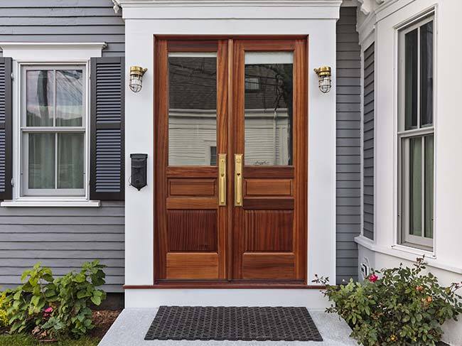 A large brown front door on a grey weatherboard house