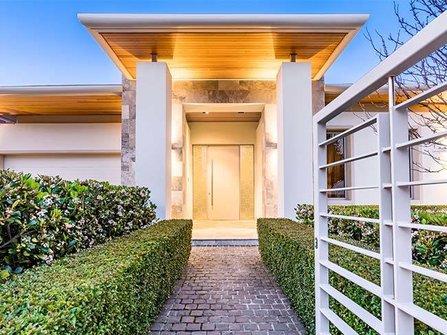 The trim entryway to a large, modern, cream house