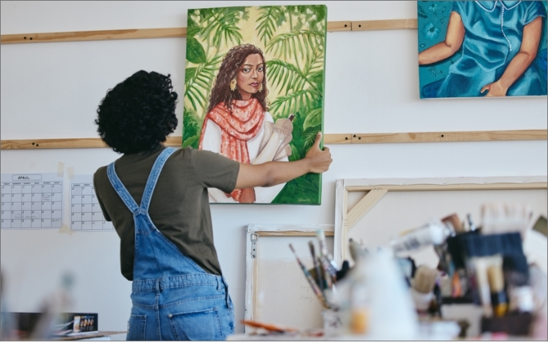 A woman stands in a studio admiring the piece of art she'd just completed