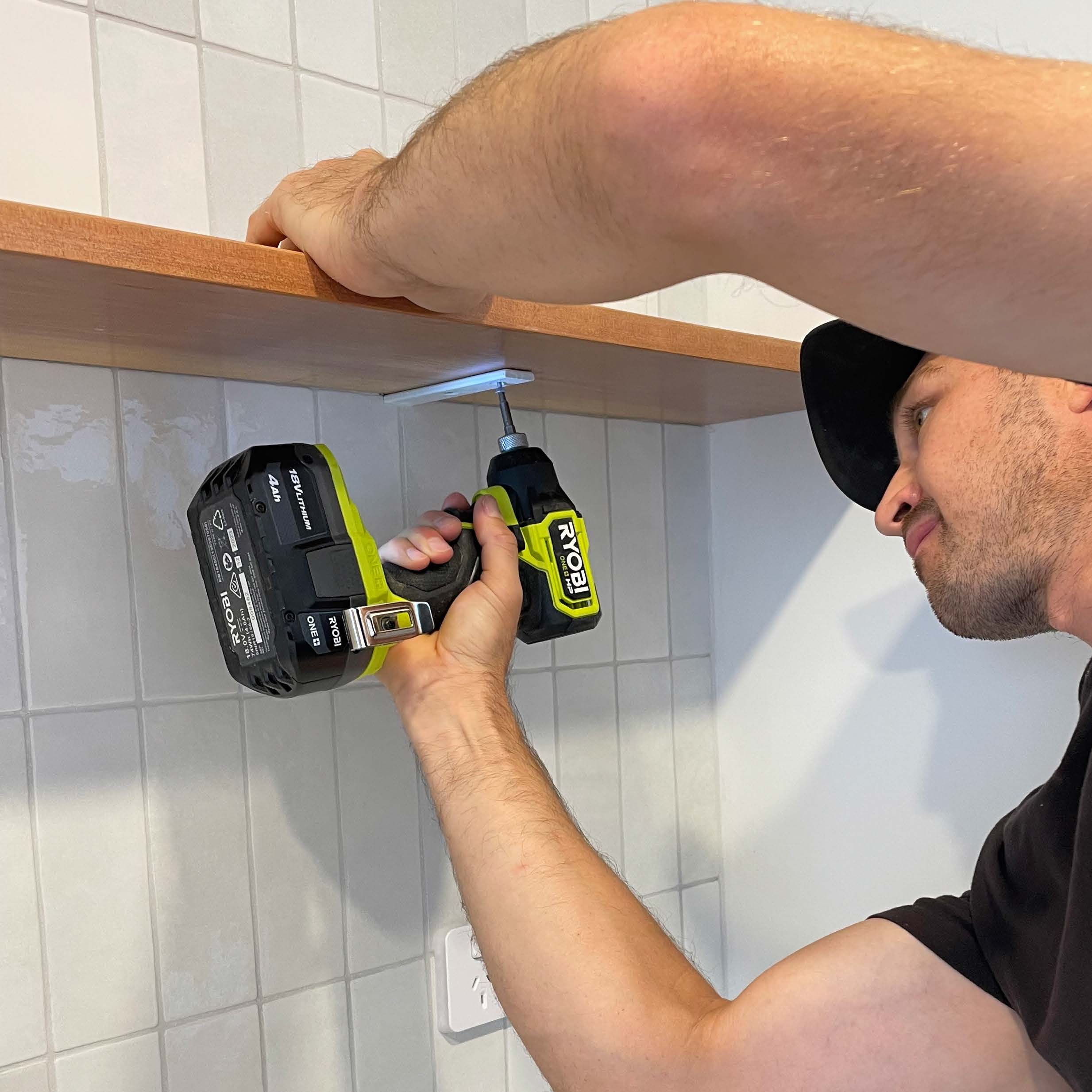 Using a RYOBI Drill Driver to secure brackets to shelf