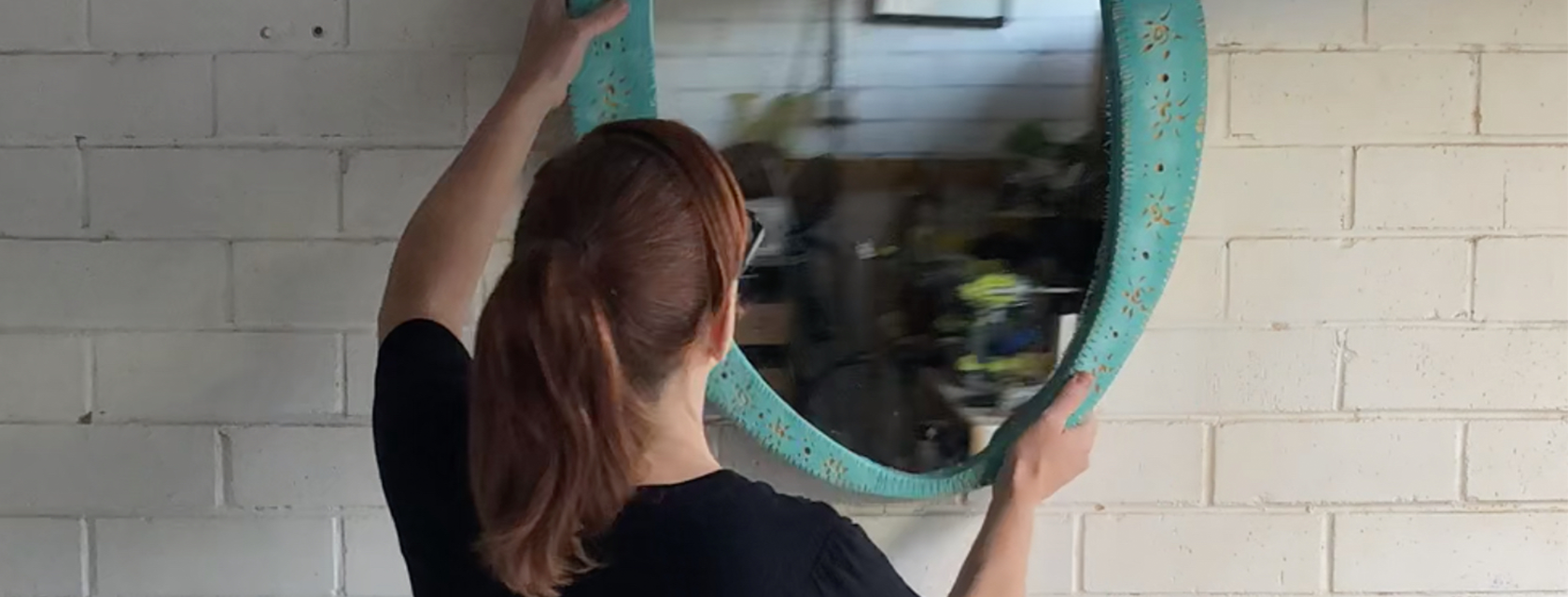 Natasha hangs her DIY ornate mirror frame on a white brick wall