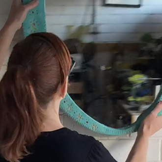 Natasha hangs her DIY ornate mirror frame on a white brick wall