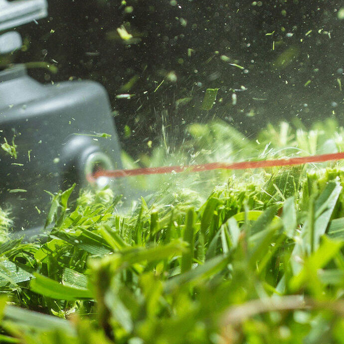 A close up image of a Ryobi line trimmer head cutting grass