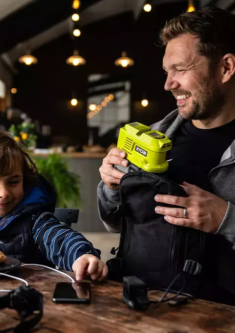 A family having lunch and using a RYOBI Battery Topper to charge their devices