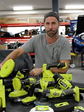 Blair Joscelyne from Mighty Car Mods standing with a pile of RYOBI tools