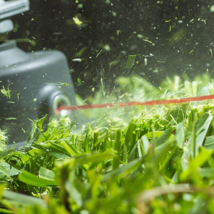 A close up of a line trimmer head in action